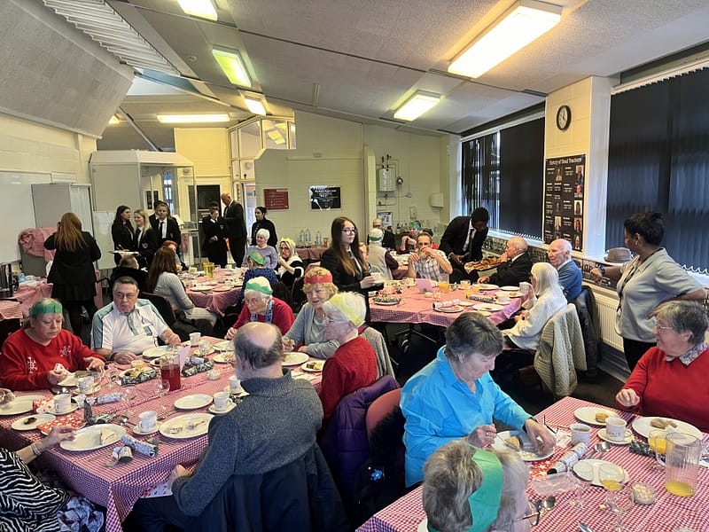 Elderly people enjoying a Christmas lunch with some Lyndon Learners