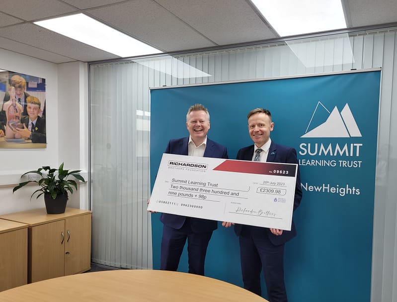 Two men standing next to each other holding a large cheque
